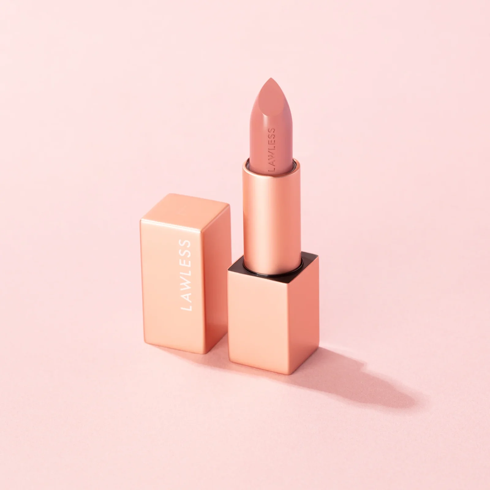 Pink lipstick tube and cap on a soft pink field.