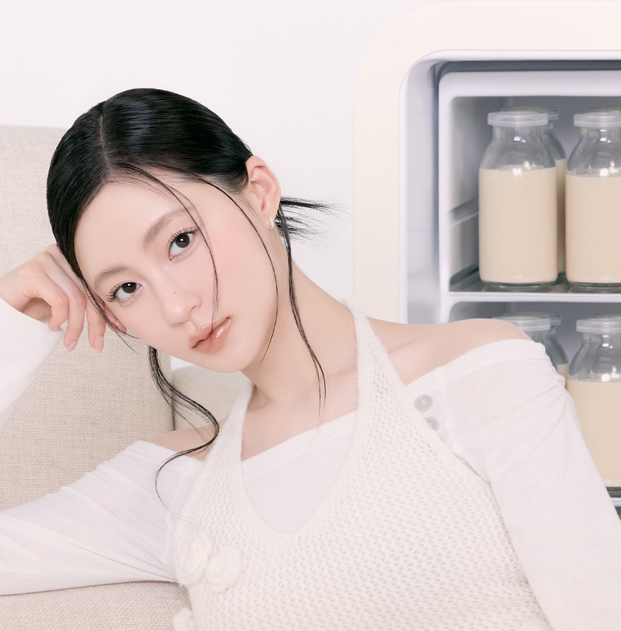 Portrait in soft daylight beside a shelf of glass bottles.